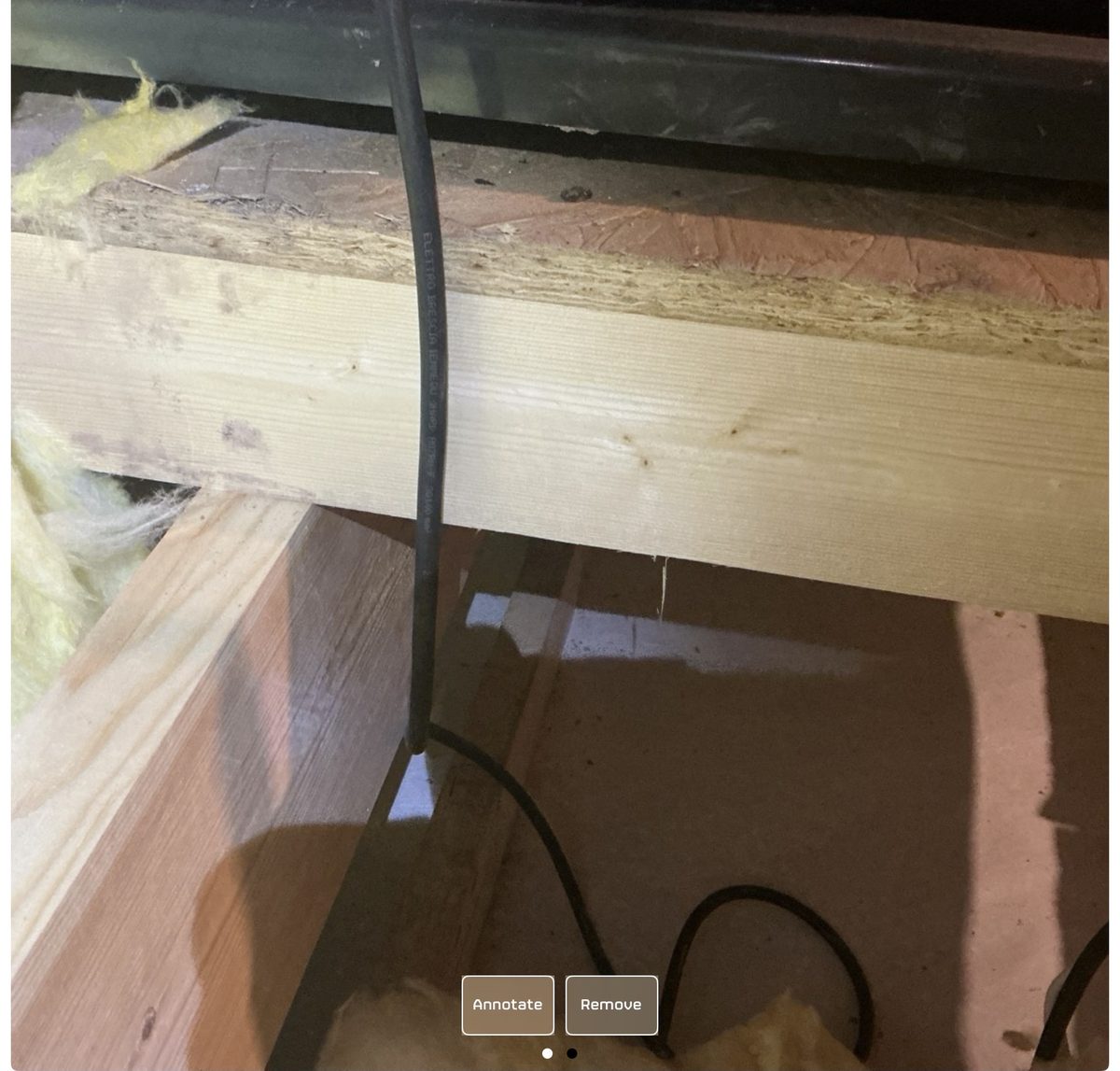 Cold-water tank in attic with no insulation underneath, photographed during a snagging inspection