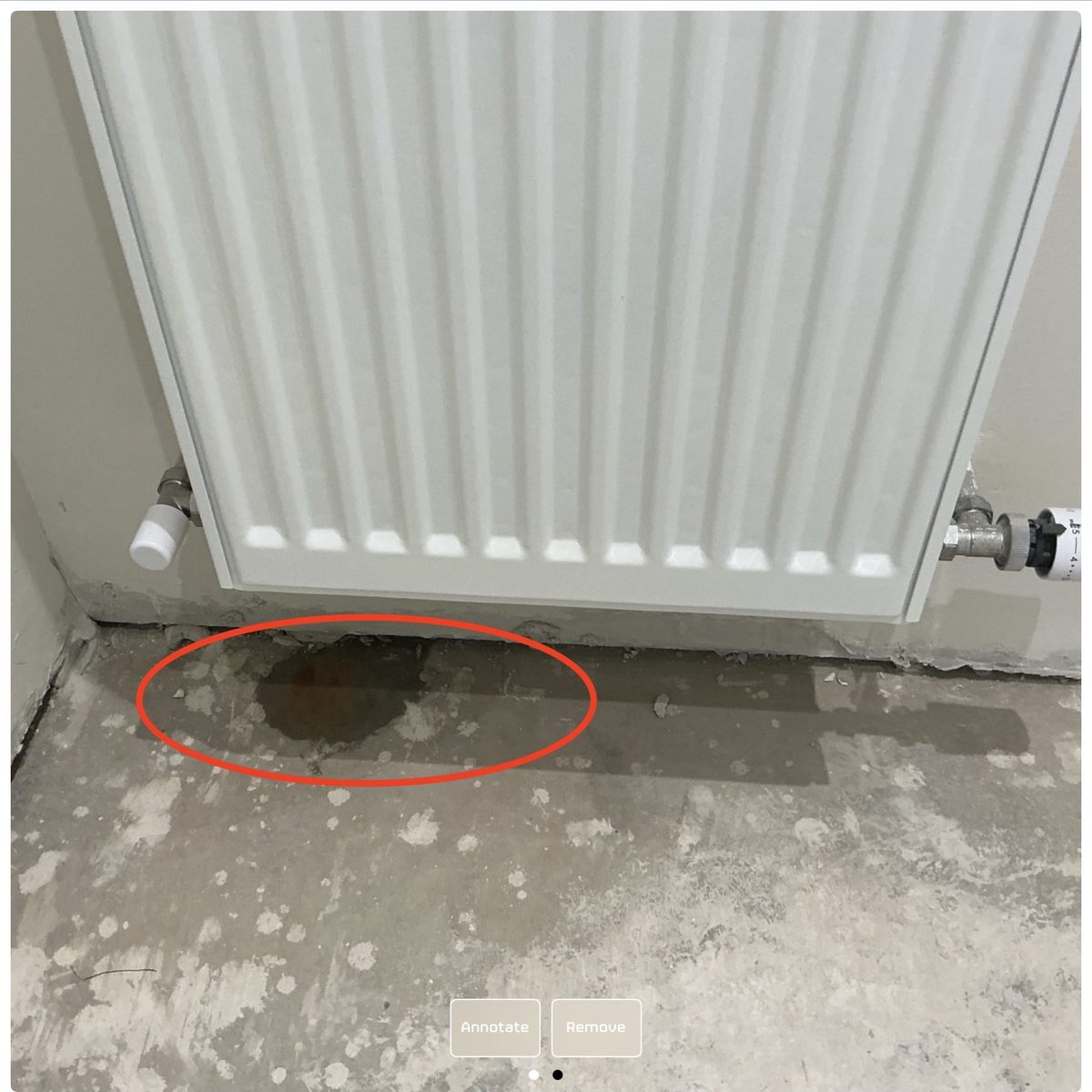 Water pooling on the floor under a leaking radiator in a guest toilet