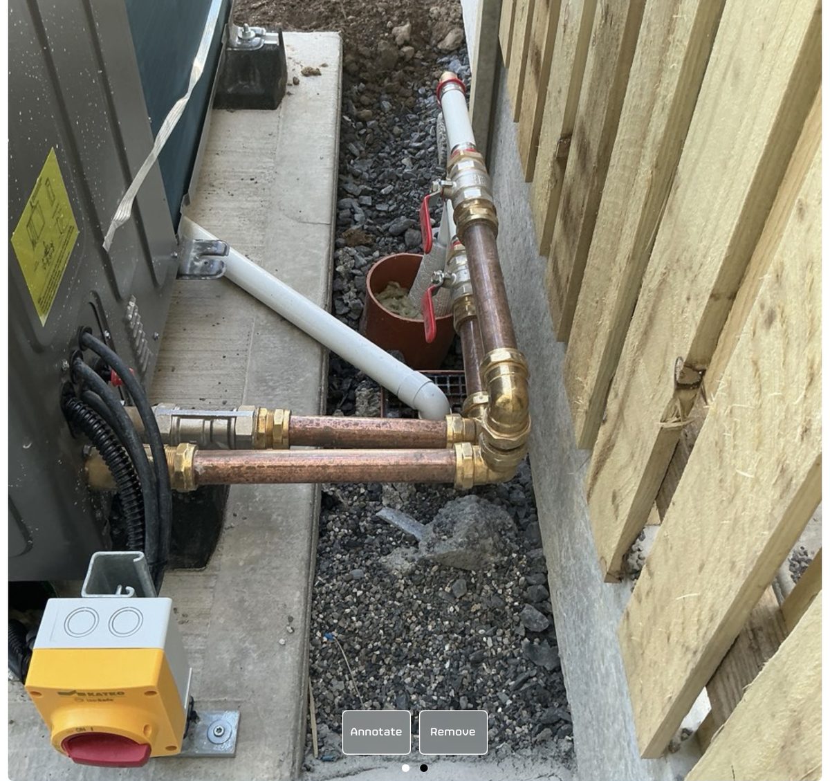Uninsulated copper pipework running from an air-to-water heat pump in a back garden